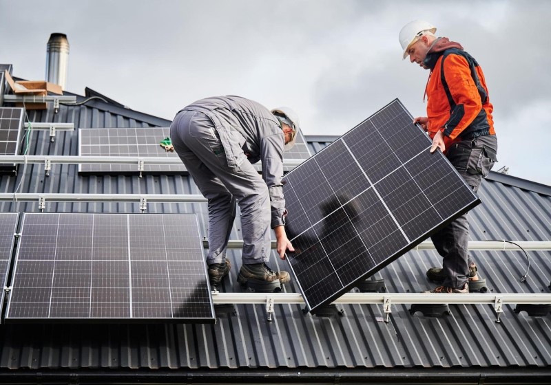 two experts installing solar panels on a roof